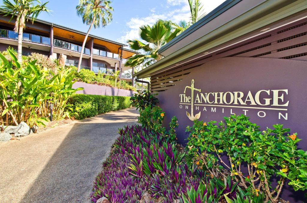 a sign for the entrance to a building with purple flowers at Anchorage in Hamilton Island