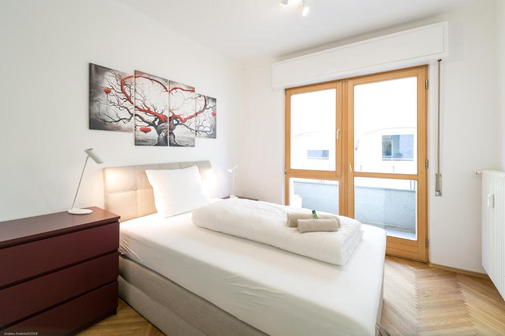 a white bedroom with a bed and a window at Apartment Duomo in Bolzano