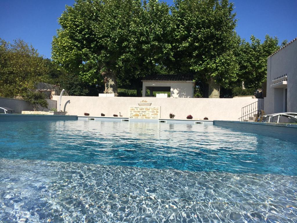 a swimming pool with blue water in front of a building at DOMAINE FORVENT in Saint-Julien-de-Peyrolas