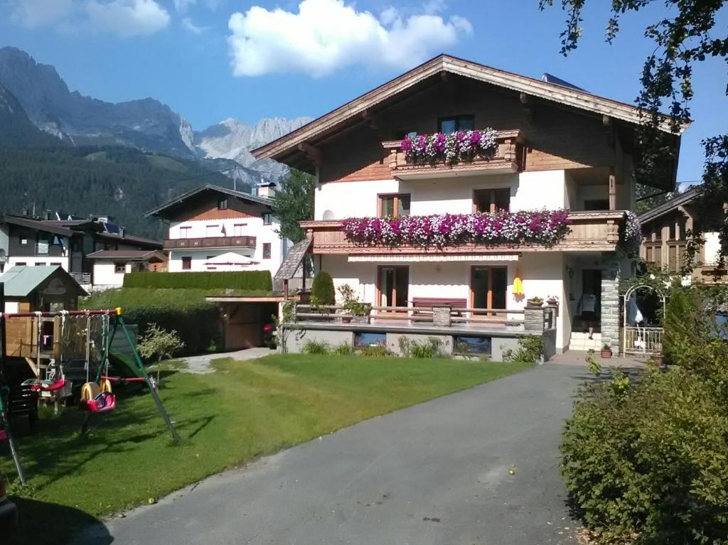 une maison dans les montagnes avec des fleurs sur les balcons dans l'établissement Ferienwohnung Innerbichler, à Ellmau