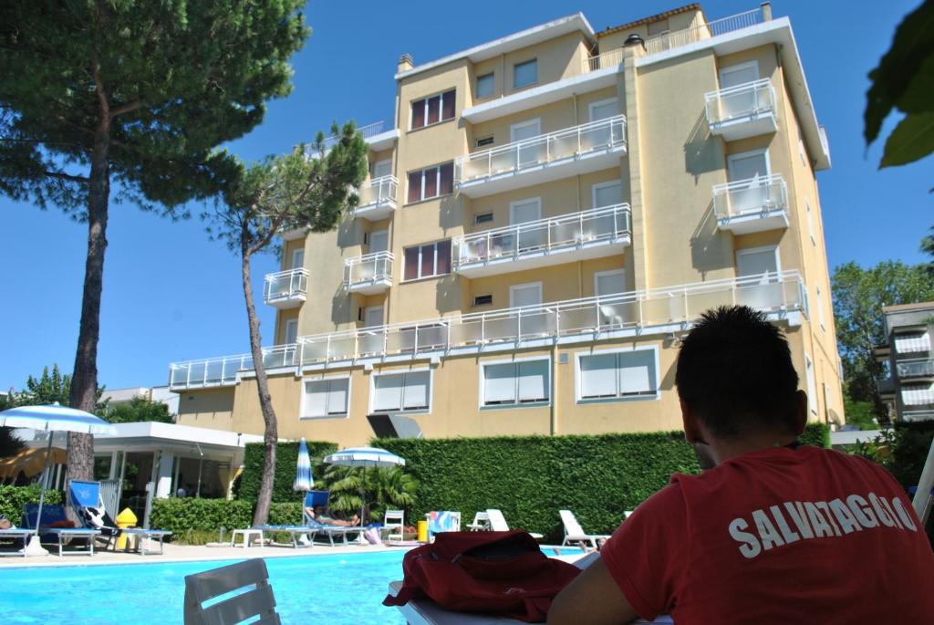 Un uomo seduto a un tavolo di fronte a un hotel di Hotel Bahama a Rimini