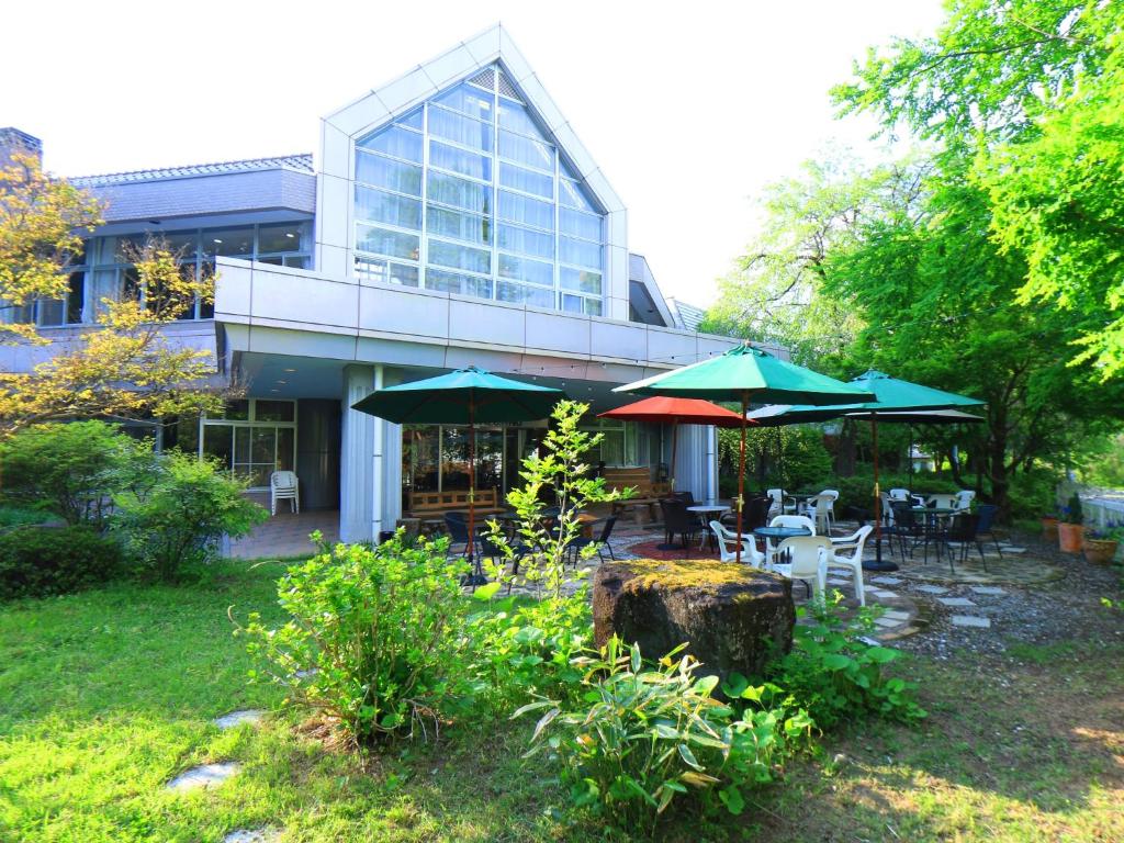 a building with tables and umbrellas in a yard at Guestroom Garden Azumino in Azumino