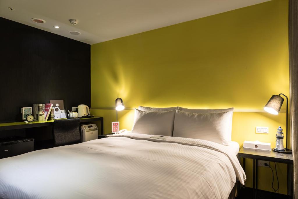 a bedroom with a white bed with a yellow wall at Vendome East Inn in Taipei