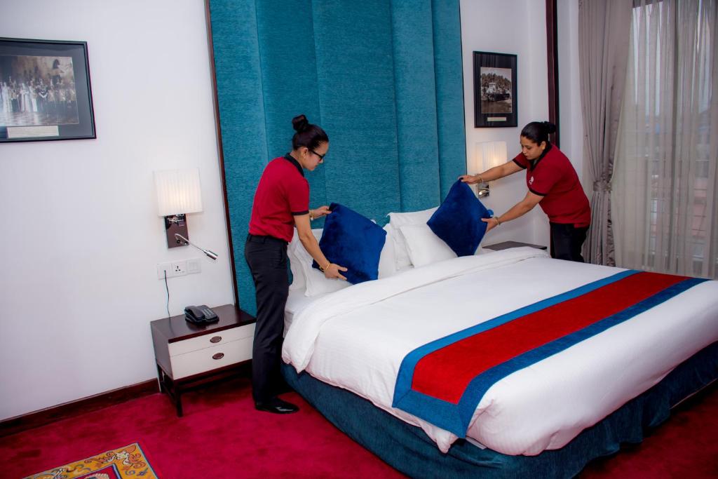 Deux femmes font un lit dans une chambre d'hôtel dans l'établissement M Hotel Thamel-Kathmandu, à Katmandou