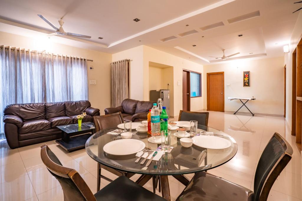 uma sala de estar com uma mesa de vidro e cadeiras em Blueberry Service Apartments em Hyderabad