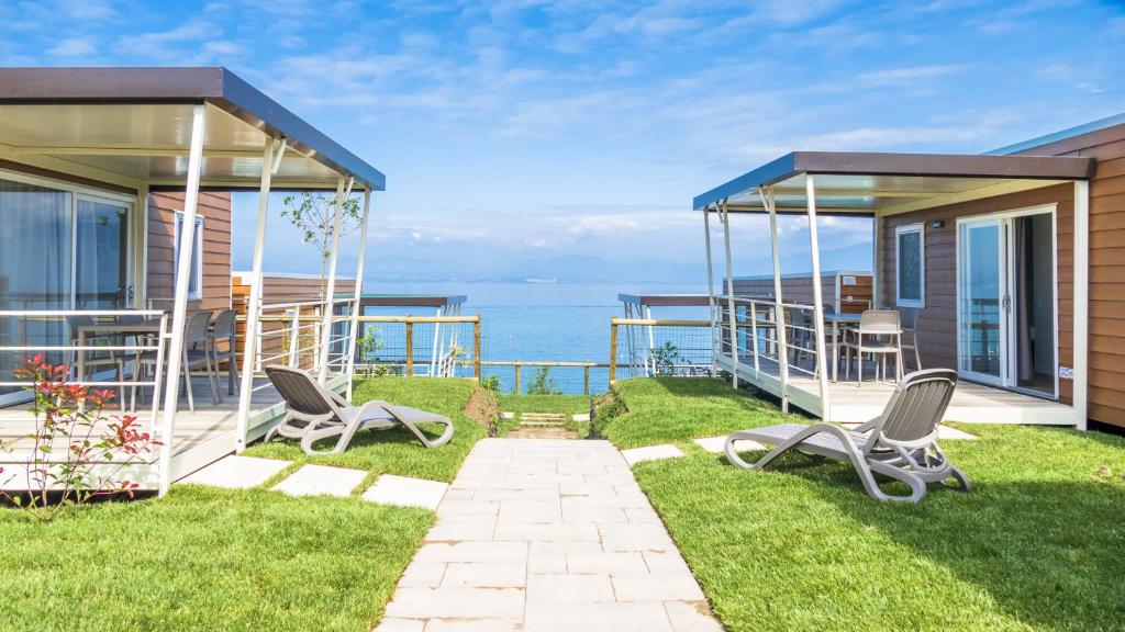 ラツィーゼにあるIdeaLazise Camping and Villageの背景に海を望む椅子2脚付きの家