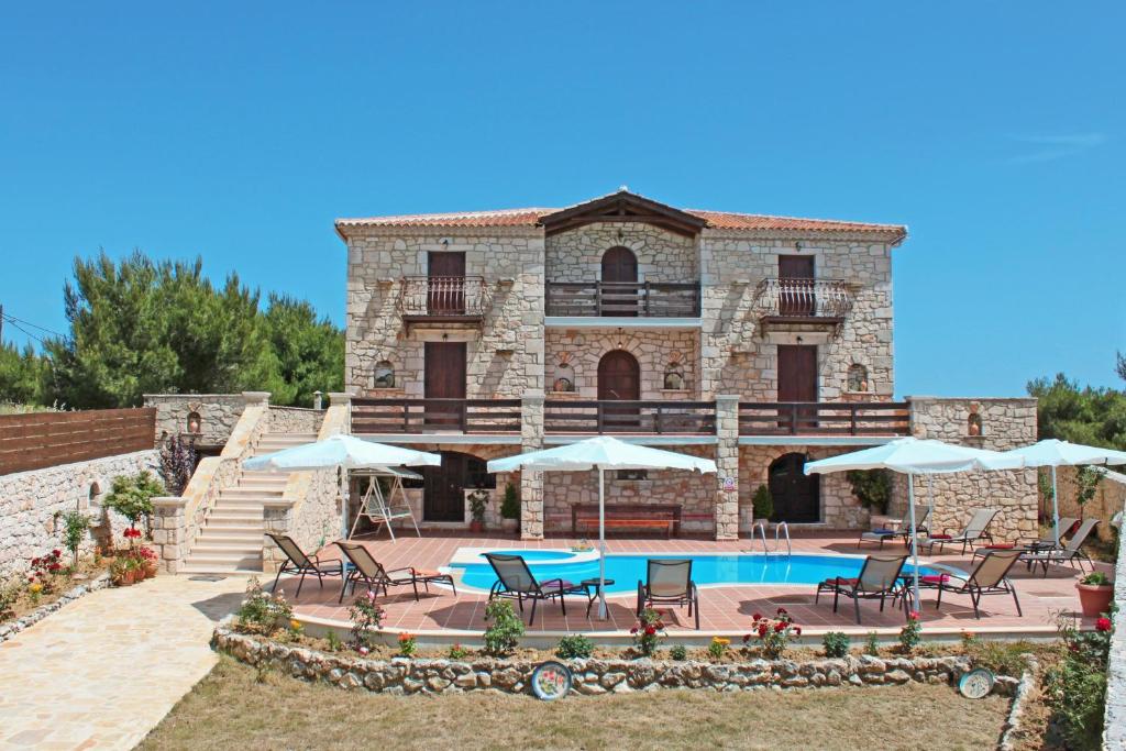 a villa with a swimming pool and chairs and umbrellas at The Vivian - Luxury Stone Villa in Koiliomenos