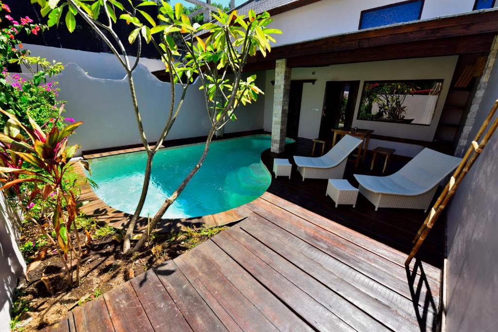 una terraza de madera con sillas y una piscina en Cantika Villa en Gili Trawangan