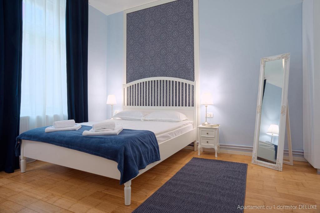 a bedroom with a bed with a blue blanket and a mirror at Republicii Residence in Braşov