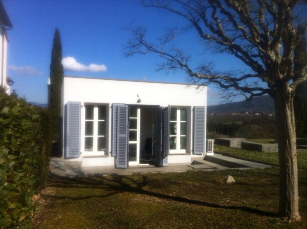 una casa blanca con persianas azules y un árbol en Firenze in collina con piscina, en Bagno a Ripoli