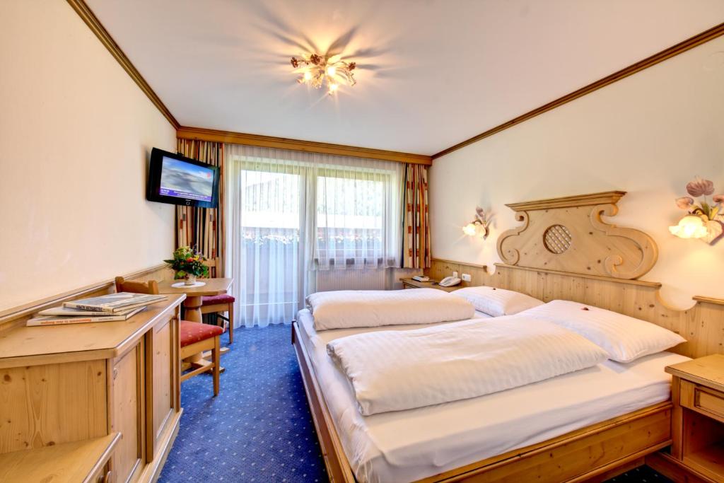 a hotel room with two beds and a desk at Hotel zum grünen Tor in Tux