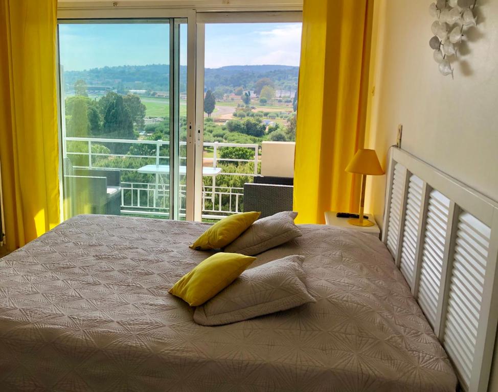 1 dormitorio con cama con almohadas y ventana grande en Résidence meublée STUDIOTEL, en Cagnes-sur-Mer