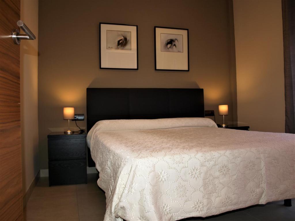 a bedroom with a large bed with two tables and two pictures at Tarragona Ciudad, El Serrallo AP-2 in Tarragona