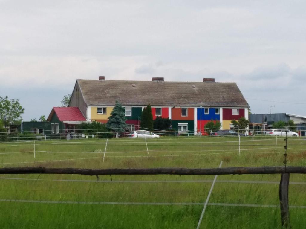 una casa colorida en un campo con una pista de tenis en Mein Marienhof en Bestensee