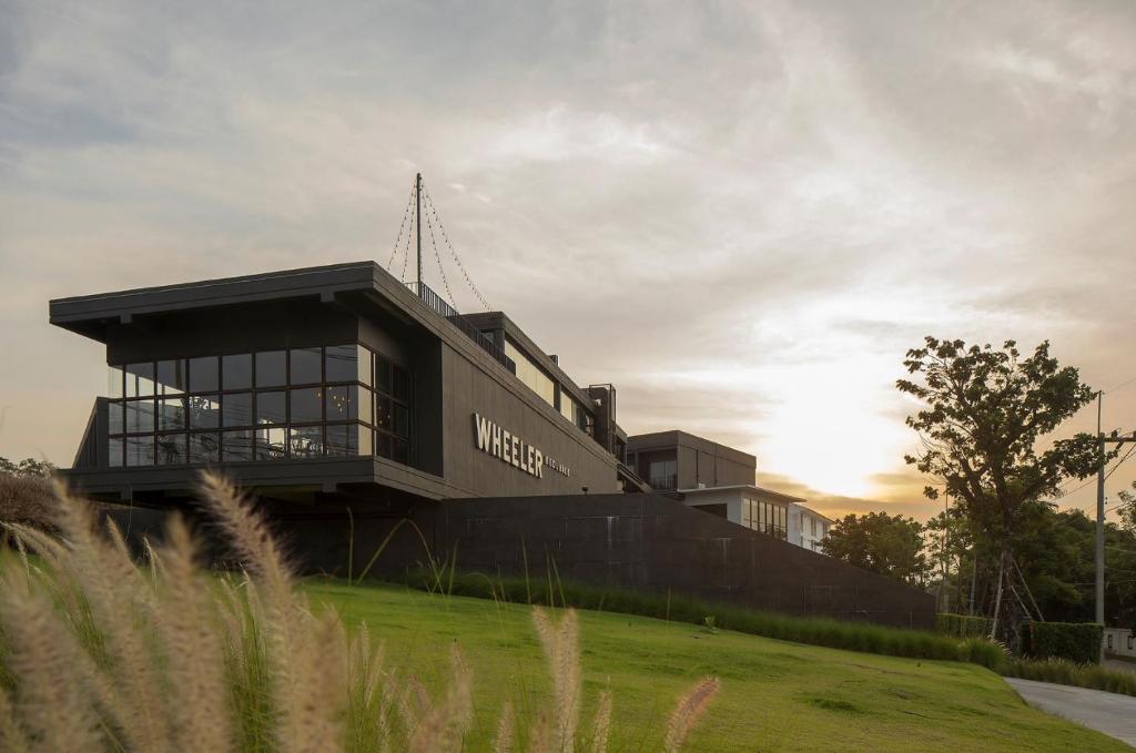 a building on a hill with the sun setting in the background at Wheeler Bed &Bike in Bangsaen