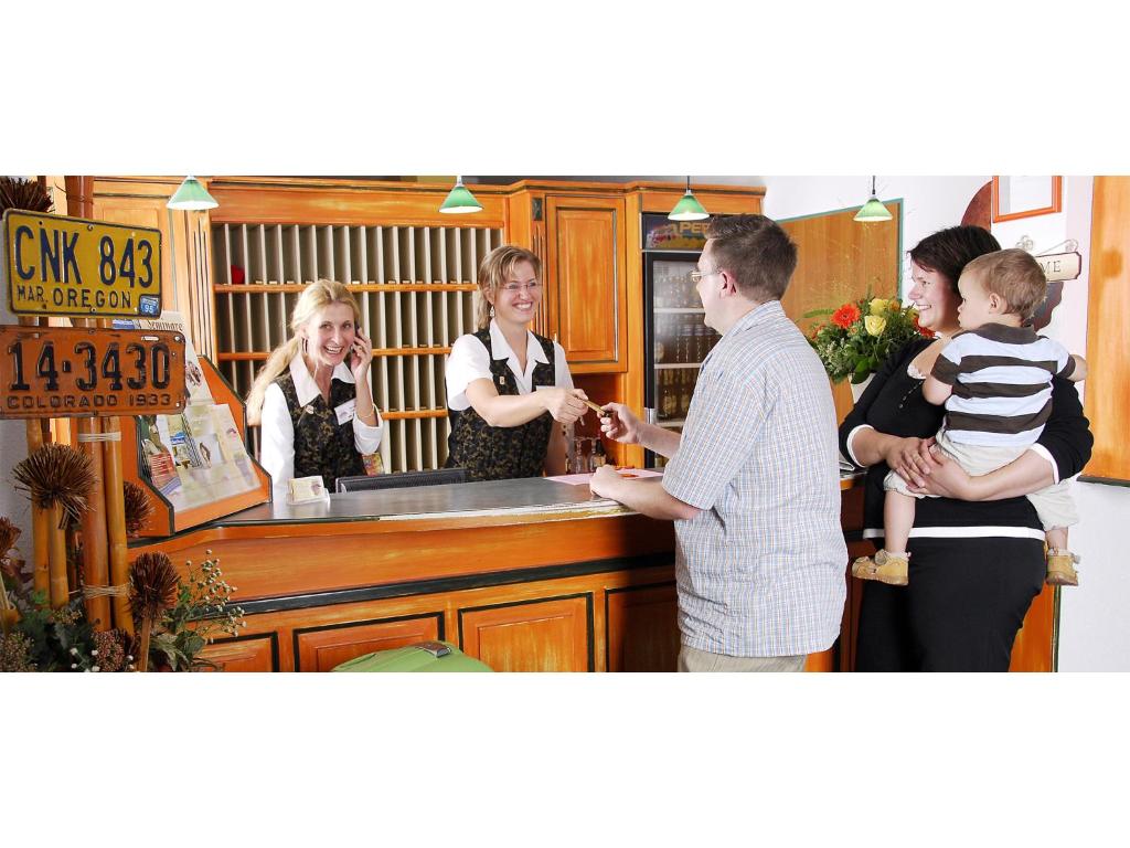 a group of people standing around a counter in a kitchen at Hotel Amerika in Bad Schussenried