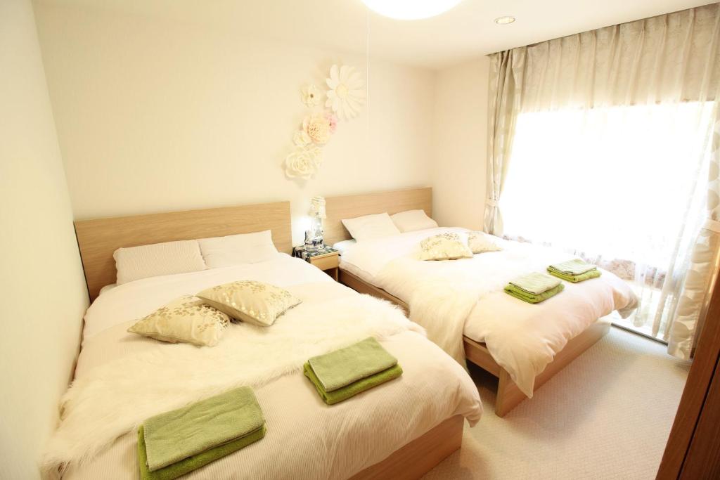 een slaapkamer met 2 bedden en groene handdoeken bij Hakone Yumoto Condominium Sakura with Hot Spring B-9 #Hs1 in Hakone