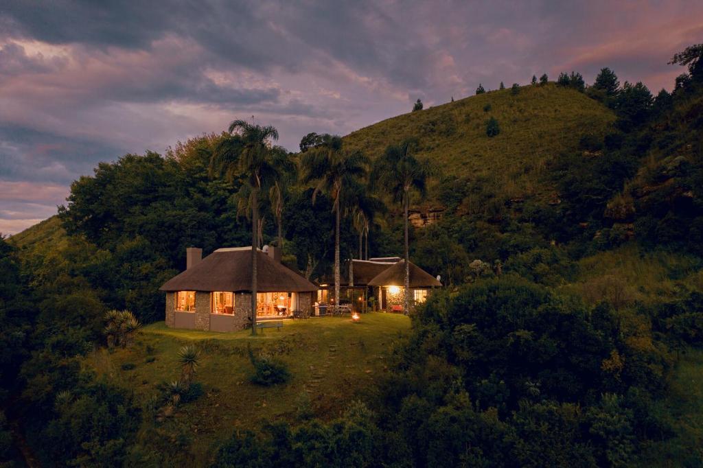 een klein huis op een heuvel 's nachts bij Mackaya Bella Country Lodge in Champagne Valley