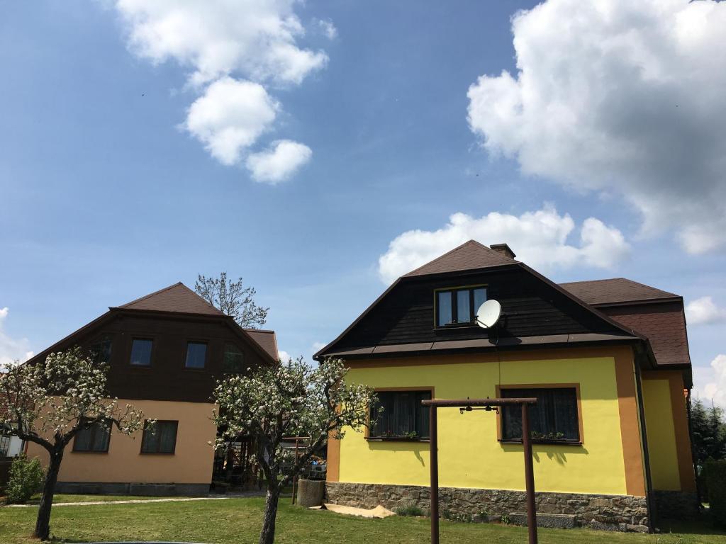 ein gelbes Haus mit schwarzem Dach in der Unterkunft Penzion Hvozd in Nová Pec