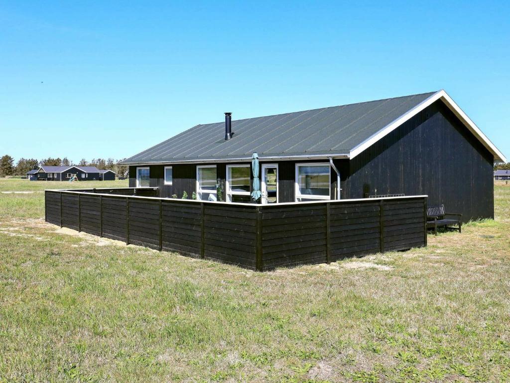 a black house with a black roof in a field at 6 person holiday home in L kken in Løkken