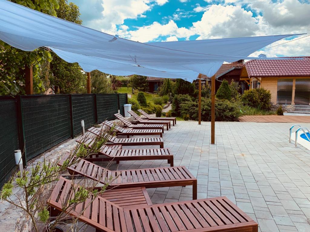 a row of wooden benches with a white canopy at Villa Rubčić in Rakovica
