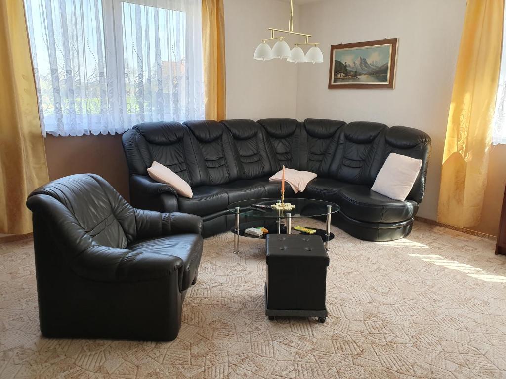 ein Wohnzimmer mit einem schwarzen Ledersofa und einem Tisch in der Unterkunft Fuchsbaude in Allrode