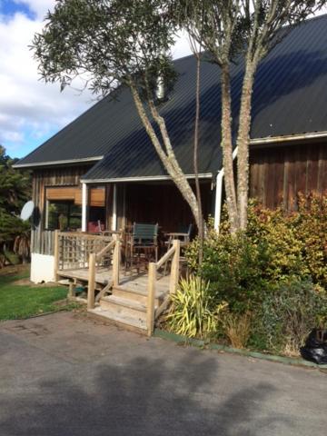 une maison avec une terrasse couverte en bois et une clôture dans l'établissement Tekoa Lodge Raurimu, à Raurimu Spiral