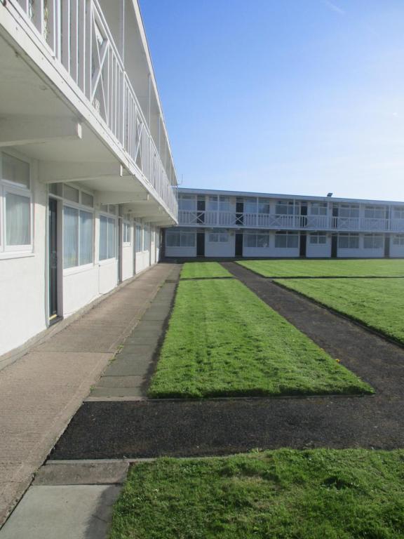 a large building with a grass field next to it at Beaches Chalets in Prestatyn