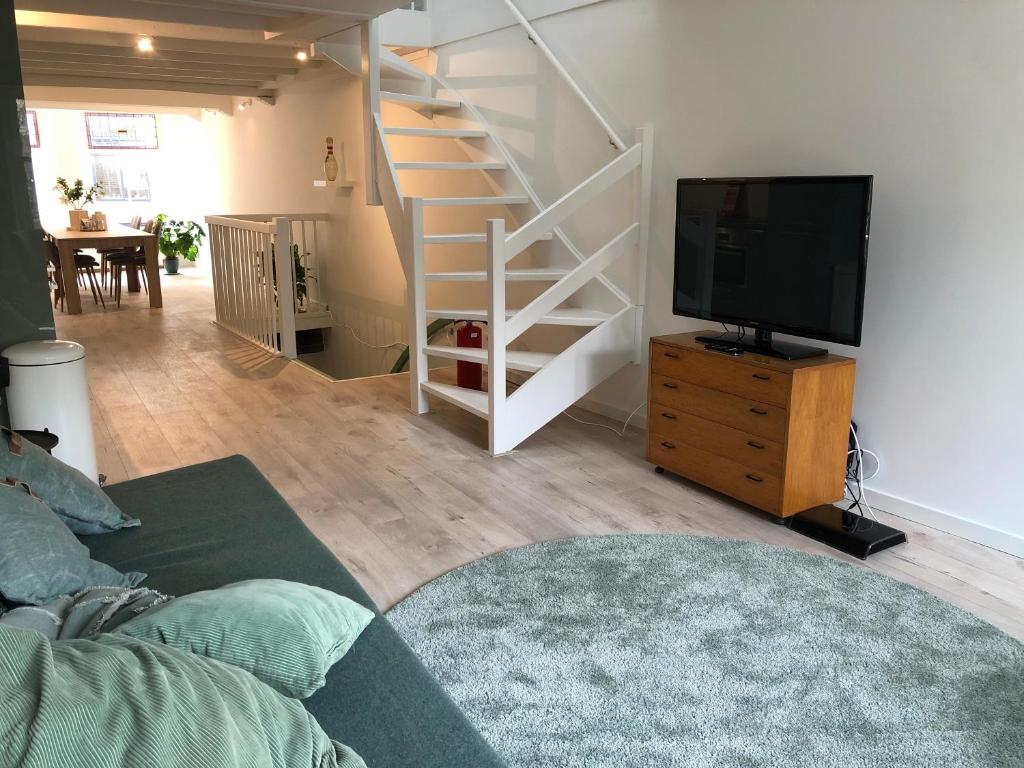 a living room with a tv and a staircase at LUXE TOPLOCATIE! Monument hartje centrum Dordrecht, 2 badkamers, 2 keukens, tuintje (10 personen) in Dordrecht