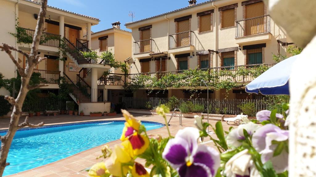 una piscina frente a un edificio con flores púrpuras en Apartamentos Valle del Guadalquivir, en Arroyo Frío