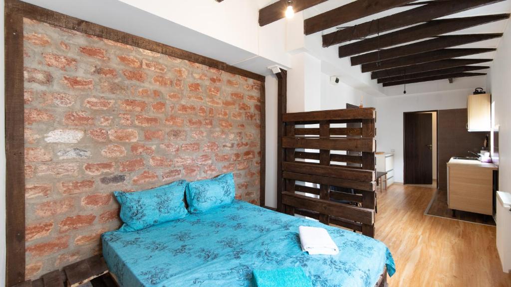 Un dormitorio con una cama azul y una pared de ladrillo en Nicole's Dorobanti Studio, en Bucarest