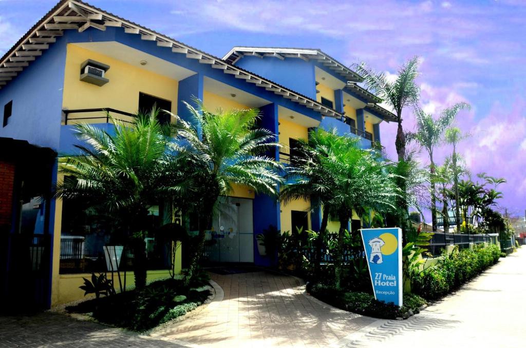 ein blaues und gelbes Gebäude mit Palmen davor in der Unterkunft 27 Praia Hotel - Frente Mar in Bertioga