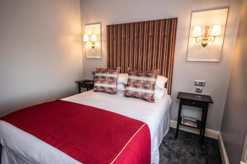 a hotel room with a large bed with a red blanket at The Georgian hotel in Coatbridge