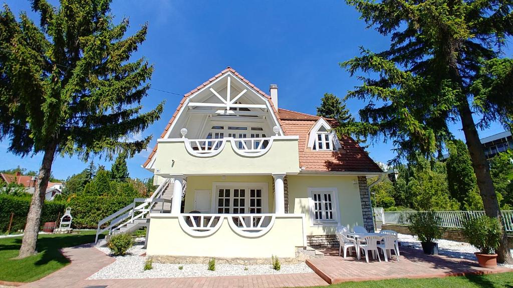 a white house with a table and chairs in front of it at Balaton Apartman Füred in Balatonfüred