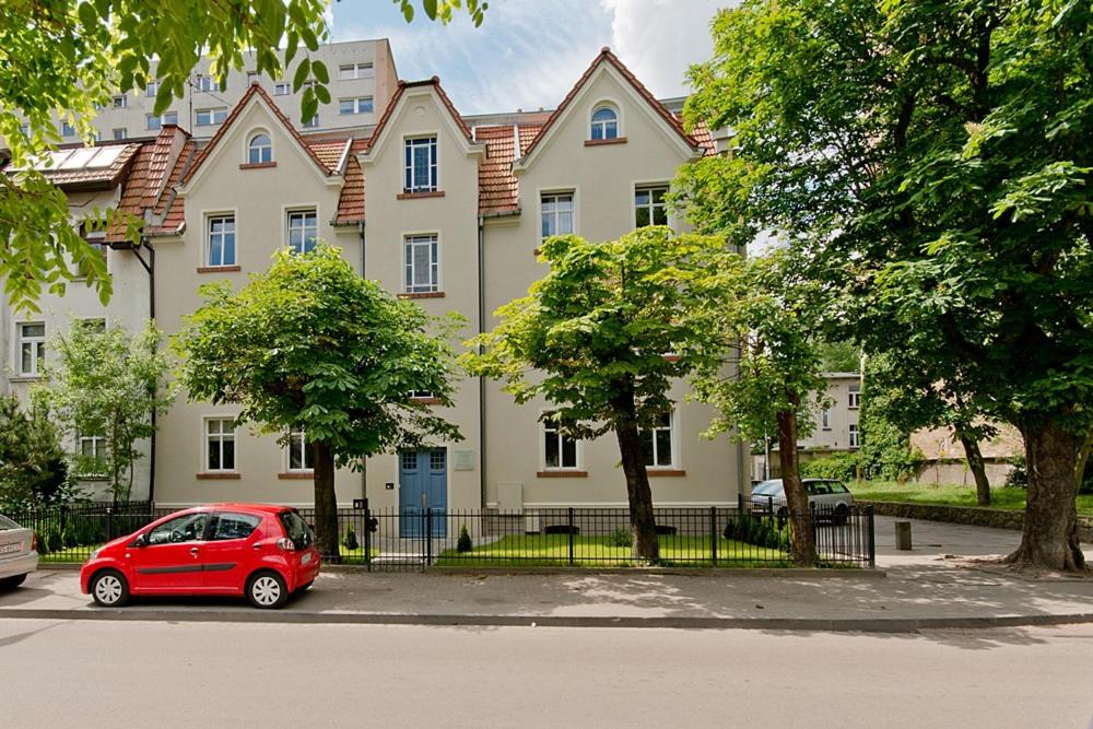 czerwony samochód zaparkowany przed dużym budynkiem w obiekcie Imperial Apartments - Balticana w mieście Sopot