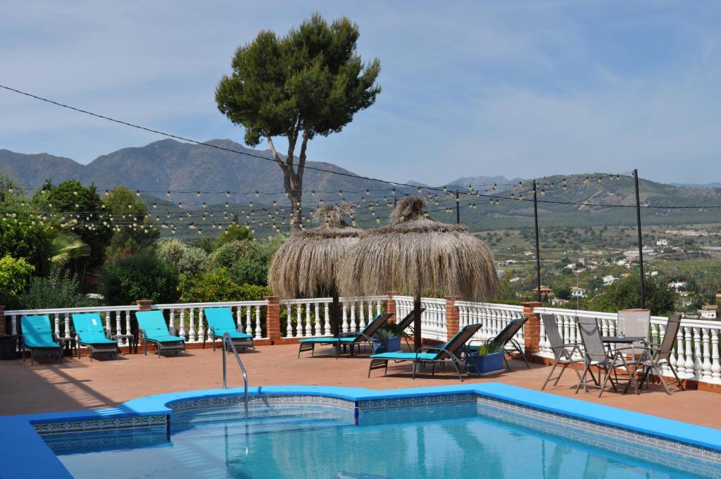 a swimming pool with chairs and a hacienda at Finca Bella Vista in Alhaurín el Grande