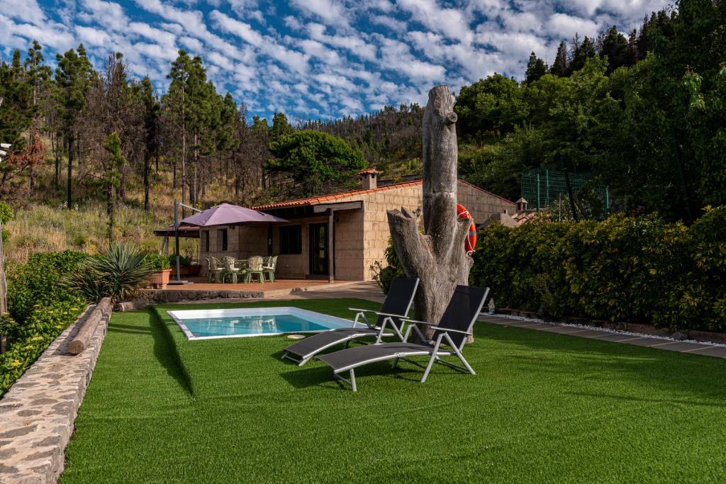 un patio con 2 sillas y una piscina en Roque nublo rural houses I, en Vega de San Mateo