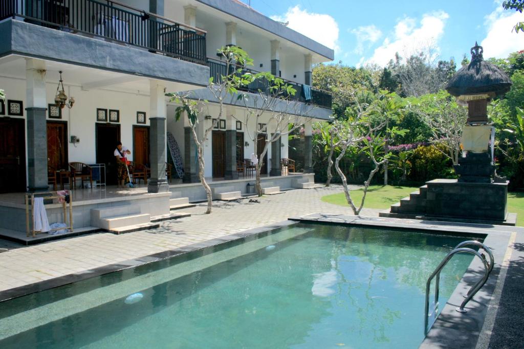 a swimming pool in front of a building at Uluwatu Made Guesthouse in Uluwatu