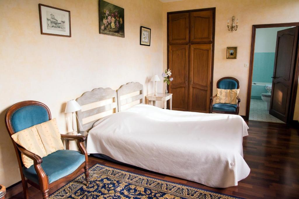 a bedroom with a white bed and two chairs at Chambres d'hôtes de charme Le Pradel in Monceaux-sur-Dordogne