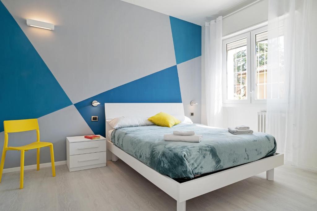 - une chambre bleue et blanche avec un lit et une chaise jaune dans l'établissement University of Bologna & Porta San Donato Apartment, à Bologne