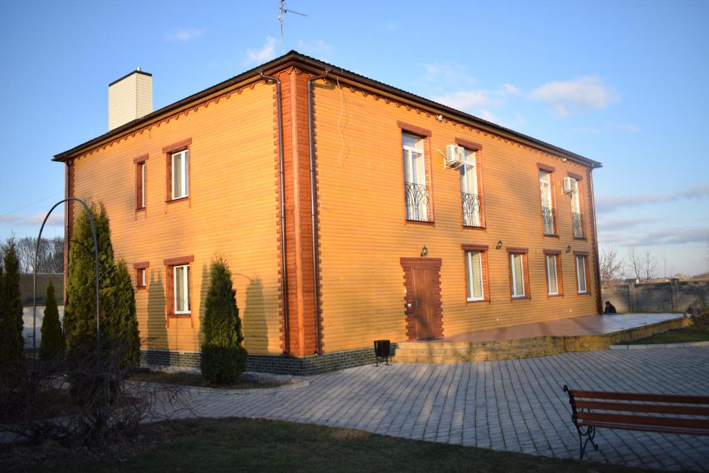 een groot houten gebouw met een deur en een bank bij Fermerska Hata in Doebno