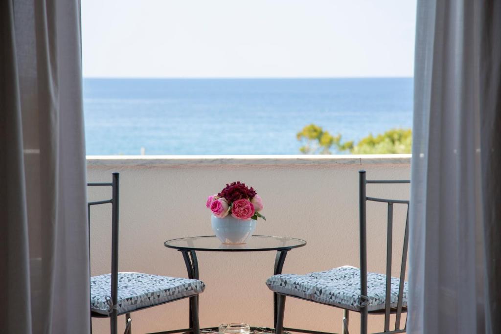 two chairs and a table with a vase of flowers on a balcony at Hotel La Mandorla in Ischia