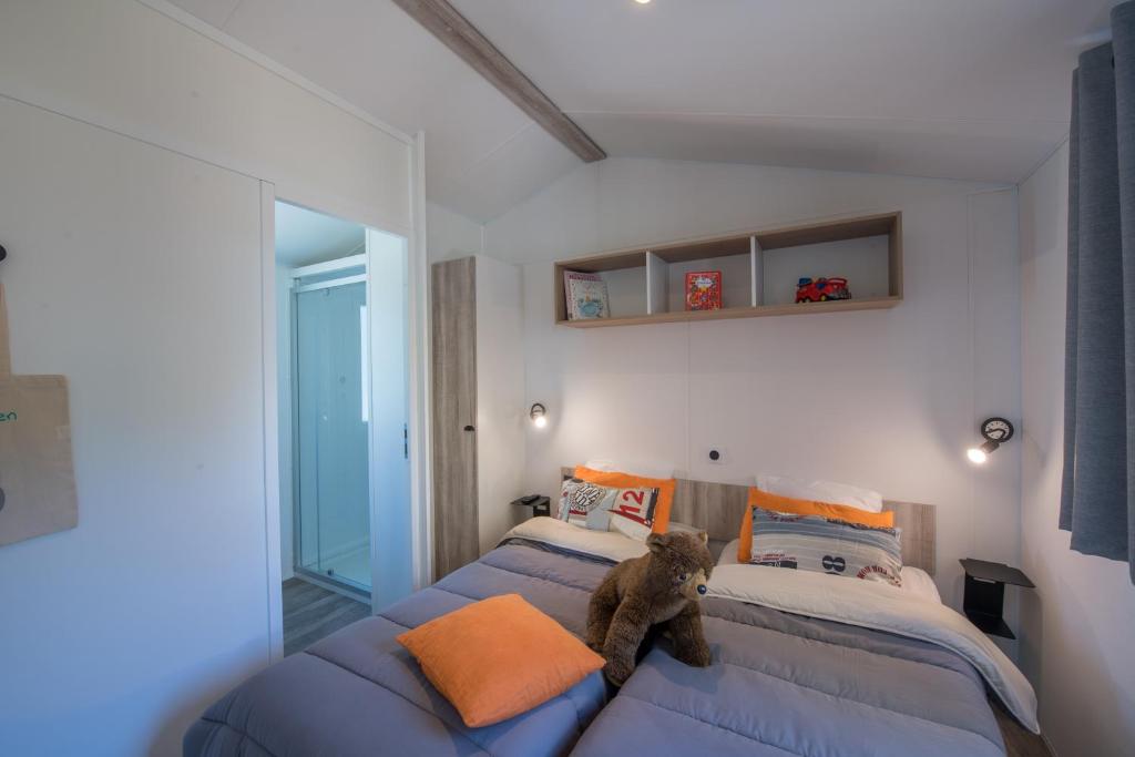 a bedroom with two beds with a teddy bear sitting on the pillow at Camping Les Grenettes in Sainte-Marie-de-Ré