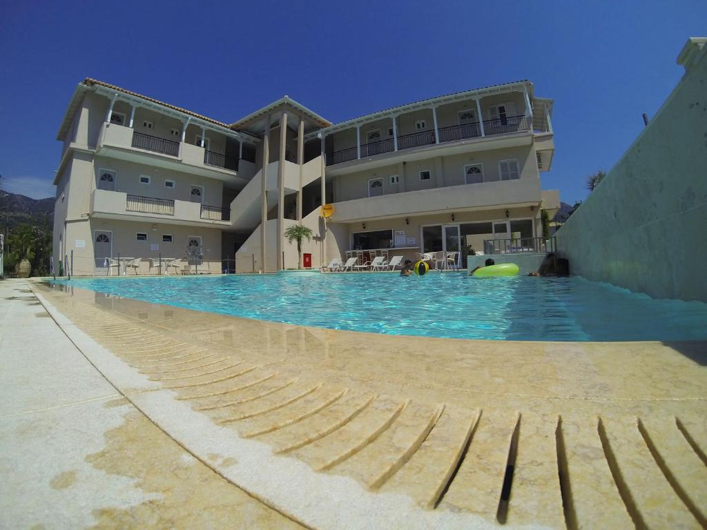 a large swimming pool in front of a large building at Happyland Hotel Apartments in Nydri