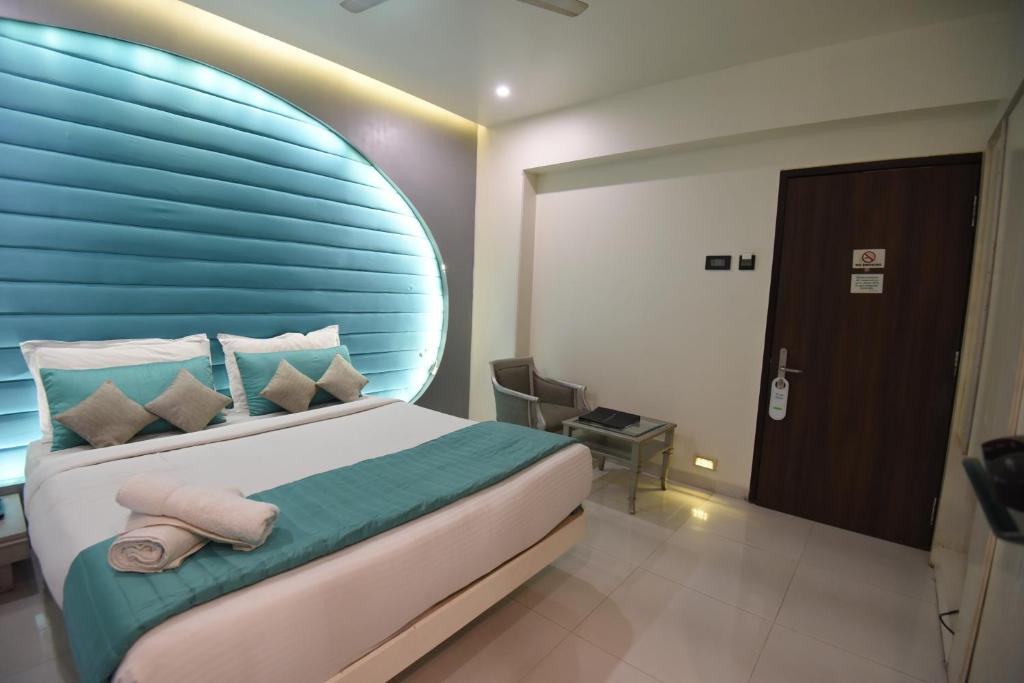 a bedroom with a large bed with a blue headboard at VITS Sharanam Thane in Thane