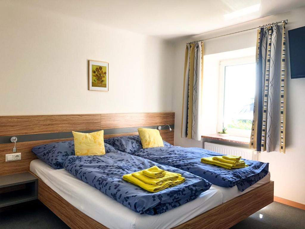 1 dormitorio con 2 camas con almohadas amarillas y ventana en Zum schwarzen Rössl, en Strengberg