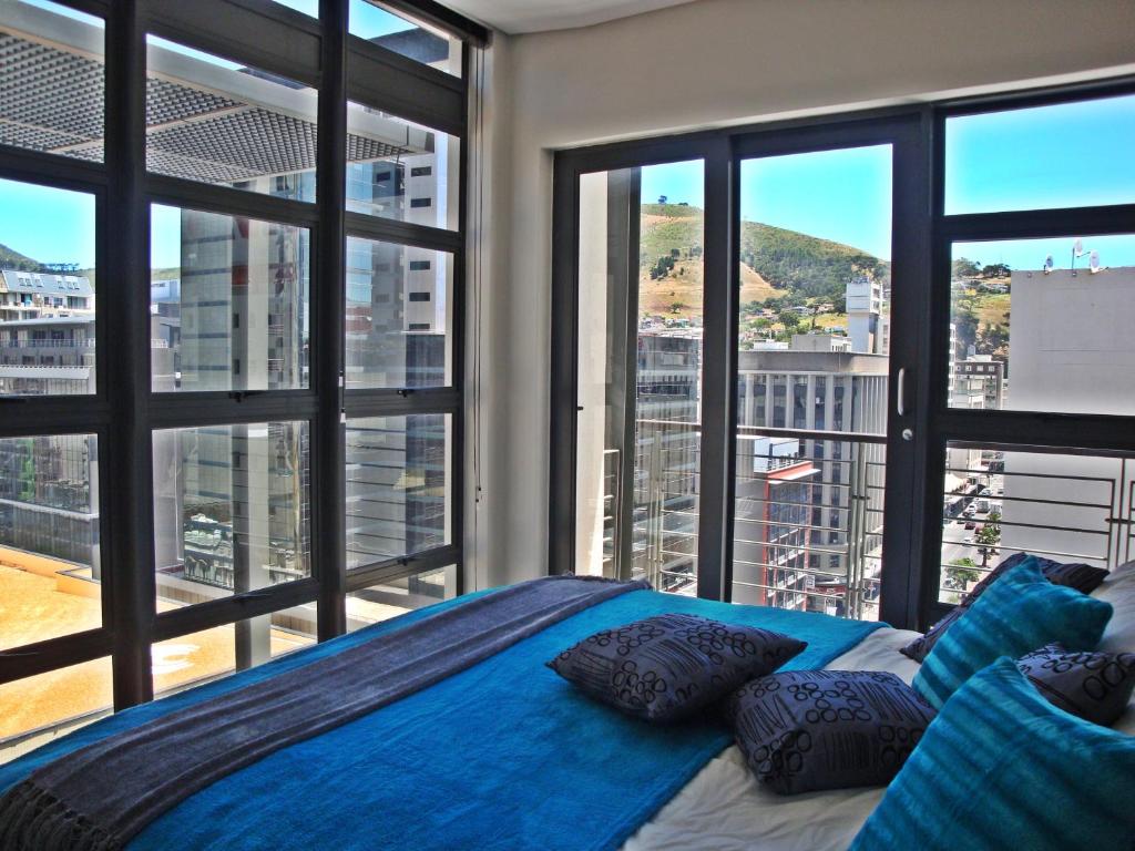 a bed with pillows in a room with windows at City Penthouse Kapstadt in Cape Town