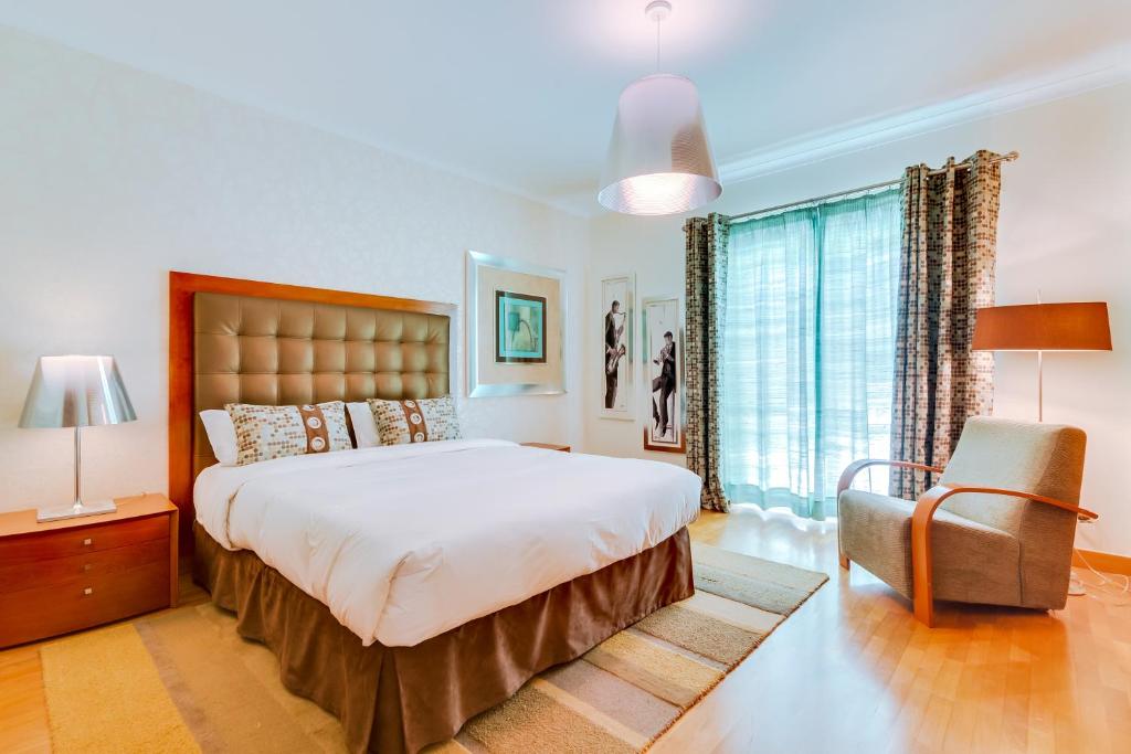 a bedroom with a large bed and a chair at OnJ Vilamoura in Quarteira