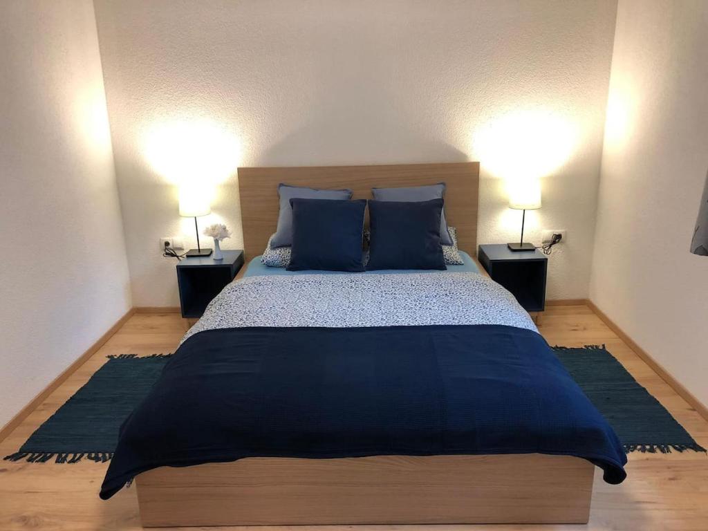 sypialnia z łóżkiem z niebieskimi poduszkami i 2 lampami w obiekcie Kleines Nest im Zentrum, eigener Eingang, Parkplatz, kostenloses Wlan w mieście Dornbirn