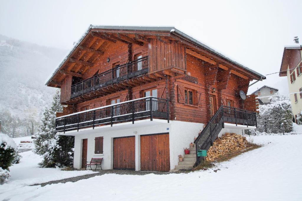 a large wooden house with a balcony in the snow at Chalet du Pre in Séez